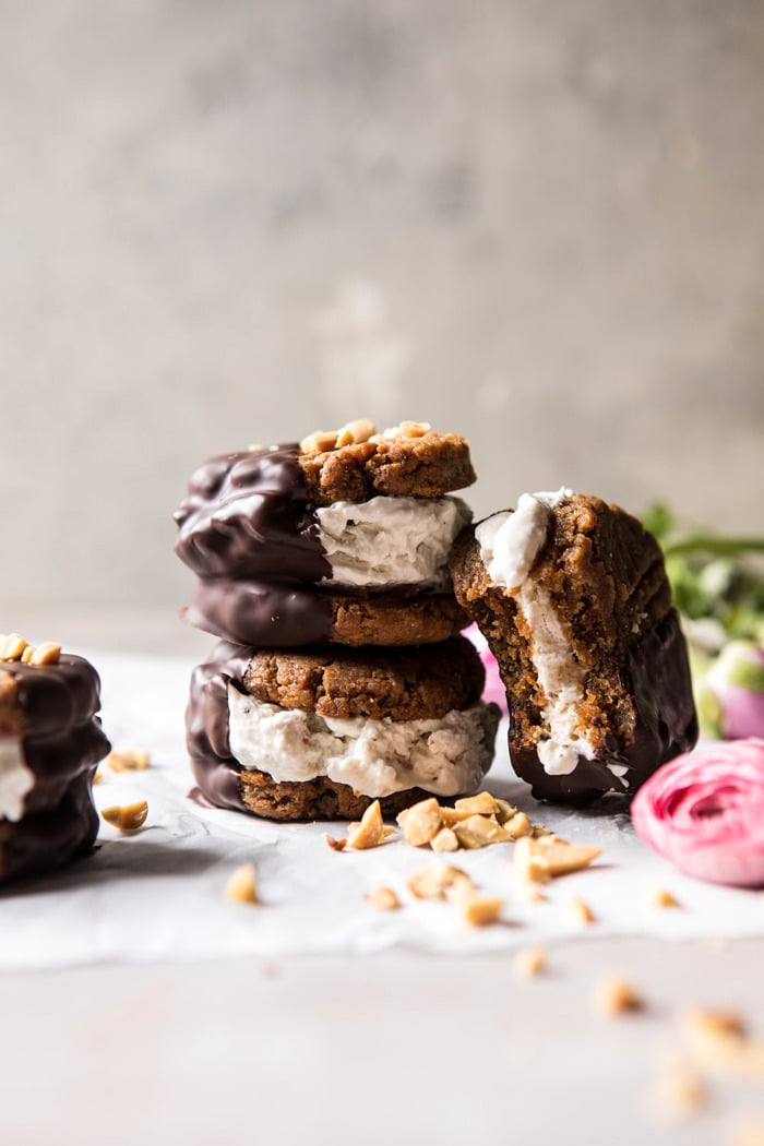 stacked, front on photo of Chocolate Dipped Peanut Cookie Ice Cream Sandwiches with bite out of one sandwich