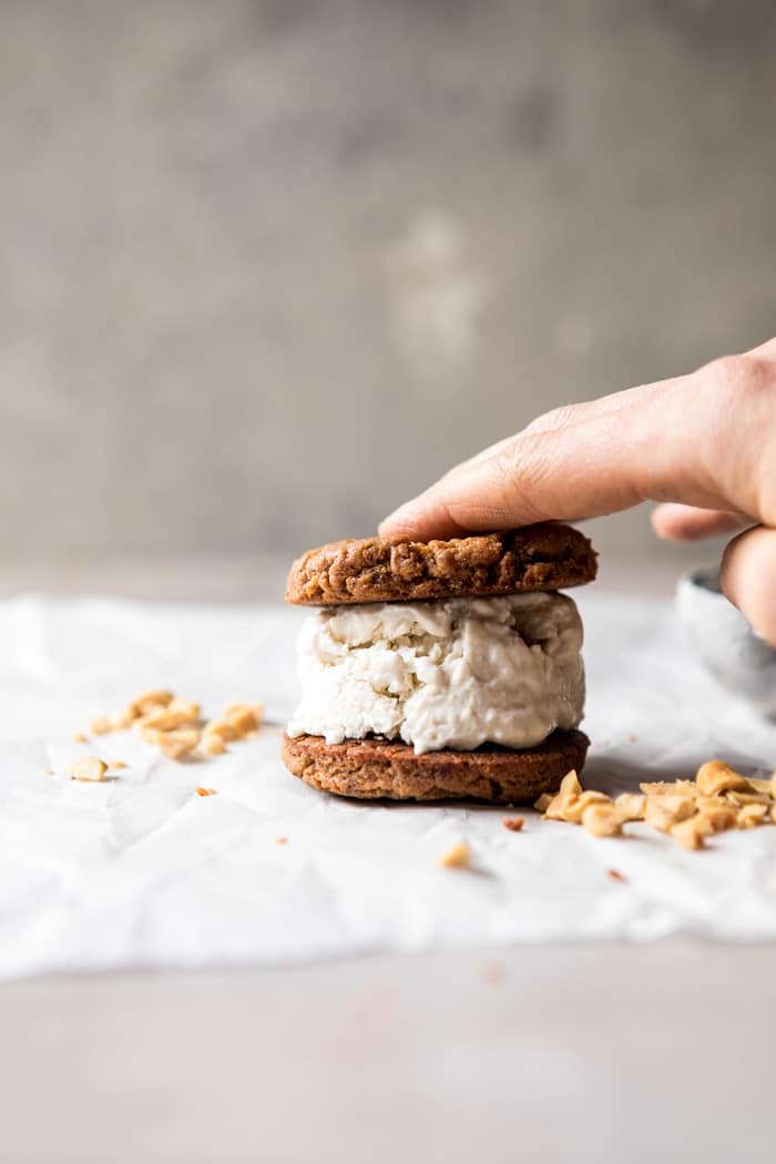 sandwiching the cookies and ice cream together for Chocolate Dipped Peanut Cookie Ice Cream Sandwiches