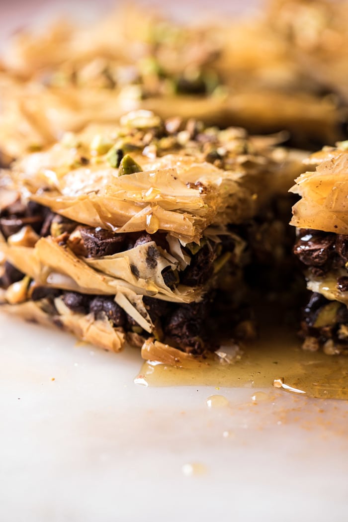 side angle photo of Easy Pistachio Chocolate Baklava with honey dripping down