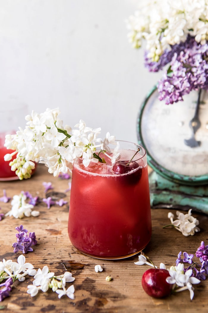angled photo of Hibiscus Cherry Vodka Spritz with lilacs and cherries