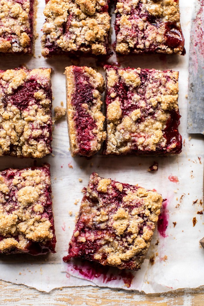 overhead photo of Buttery Raspberry Crumble Bar with one bar cut in half to show the filling