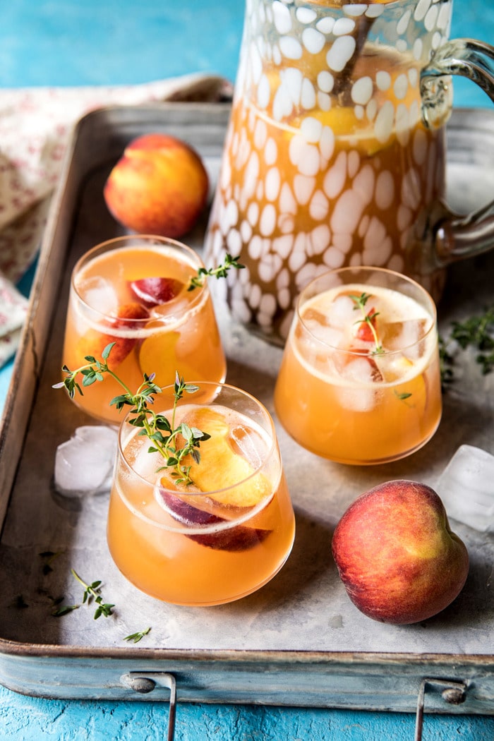 far out photo of Sweet Bourbon Peach Lemonade with pitcher and peach in photo and on a tray