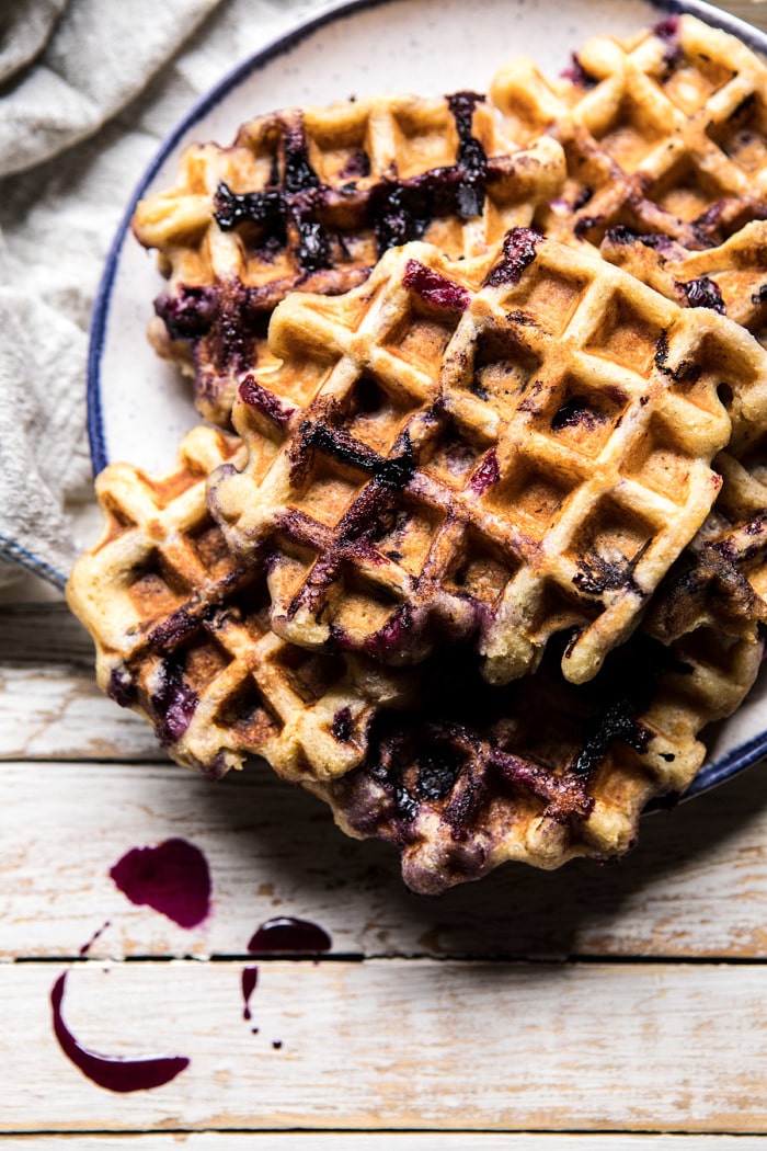 Bursting Blueberry Cornmeal Waffles with syrup and on a plate 