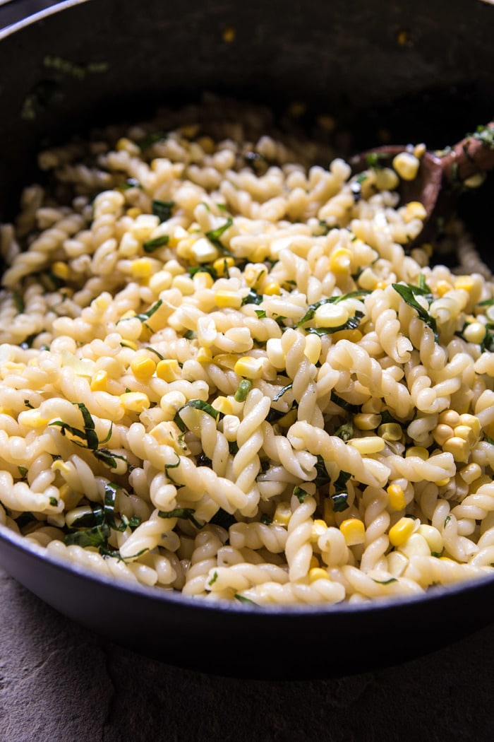 Corn, Tomato, and Avocado Pasta Salad being tossed together in bowl