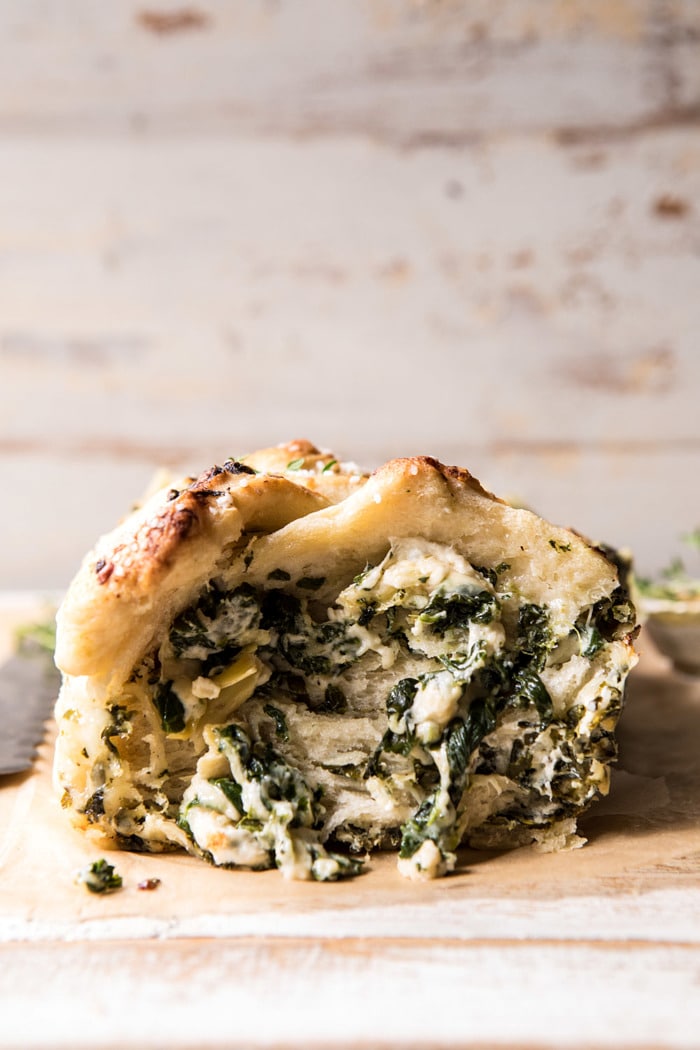 front on photo Herbed Spinach and Artichoke Pull Apart Pretzel Bread with piece missing to expose the filling