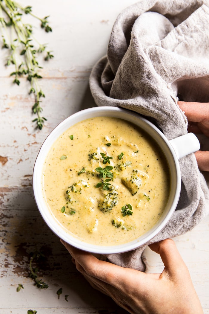 overhead photo of Instant Pot Broccoli Cheddar and Zucchini Soup with hands on bowl