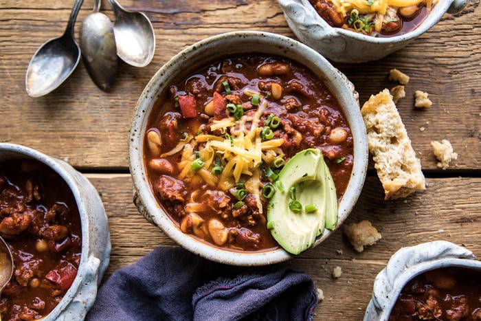 horizontal photo of Healthy Slow Cooker Turkey and White Bean Chili with beer bread and spoons in photo 