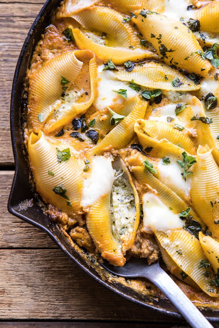 close up photo Spicy Pumpkin and Pesto Cheese Stuffed Shells with spoon in skillet