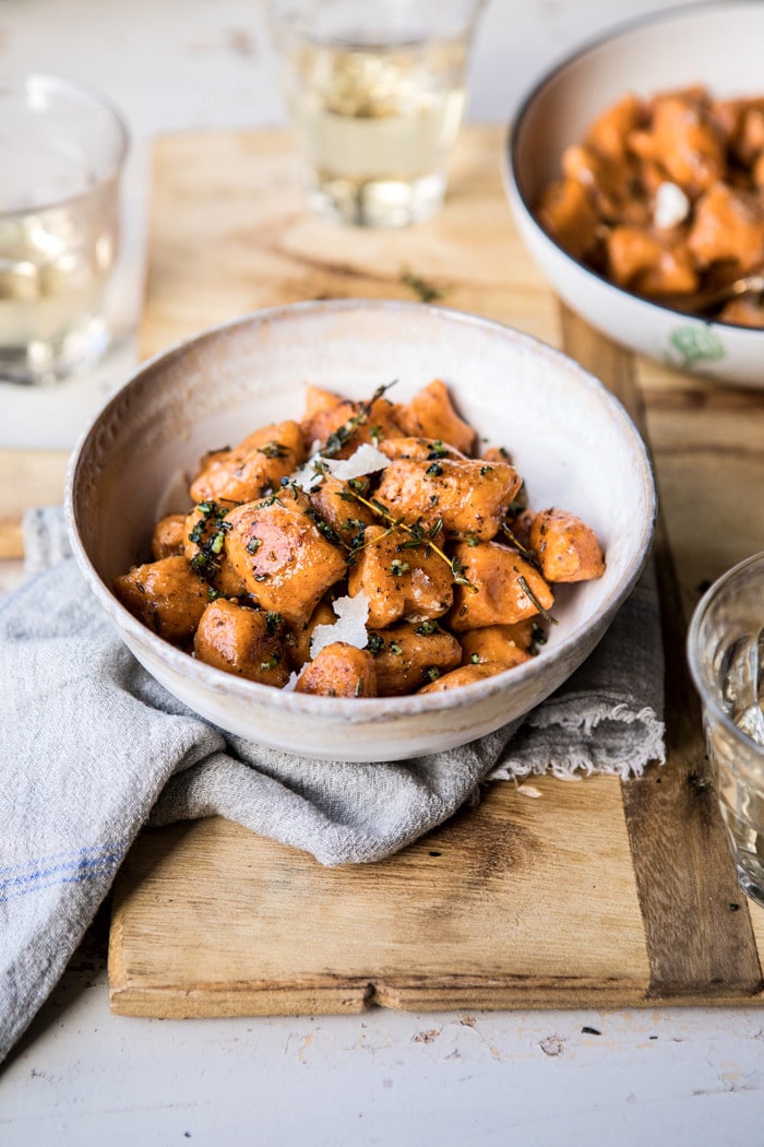 Sweet Potato Gnocchi with Herbed White Wine Pan Sauce in bowls with wine glasses and towel in photo 