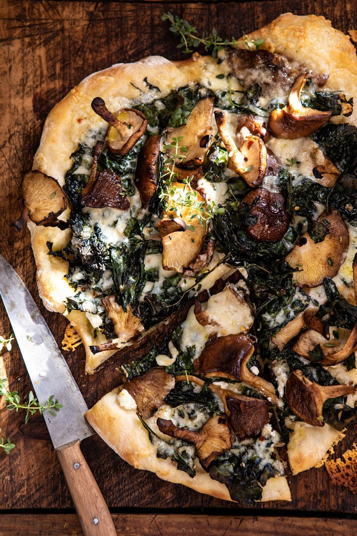 overhead close up photo of Roasted Mushroom Kale Pizza with slice cut and knife in photo