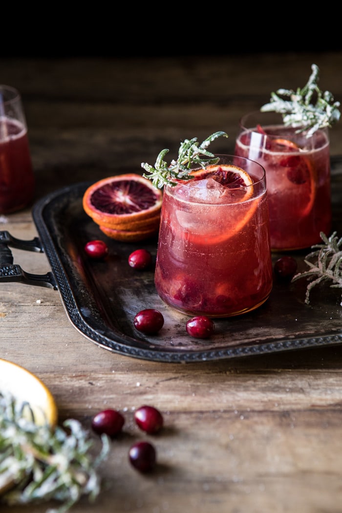 side angle photo of Spiced Cranberry Rosé Spritzers on trey with rosemary and cranberries 