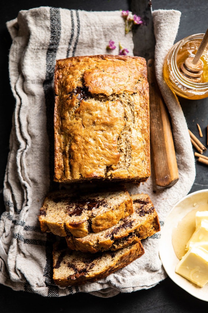 over head photo of sliced Chocolate Chunk Coconut Banana Bread with honey jar and butter on table