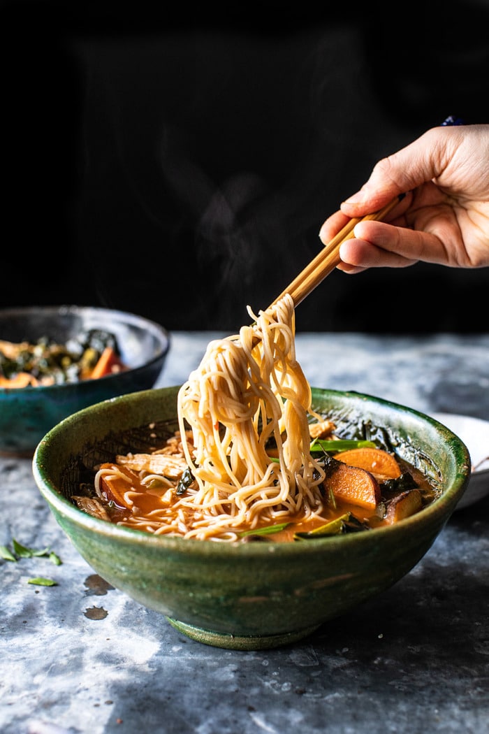 side angled photo of Feel Good Spicy Ramen with Sweet Potatoes and Crispy Shallots and noodles being pulled up out of the bowl