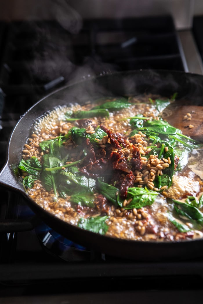 One Skillet Greek Sun-Dried Tomato Chicken and Farro on stove top cooking