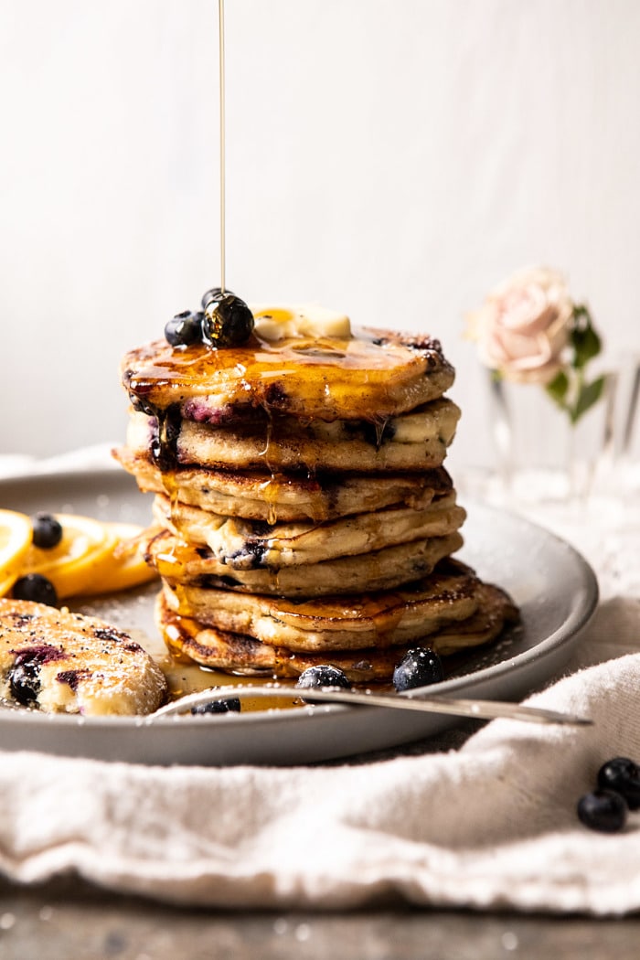 close up side angled photo of Blueberry Lemon Ricotta Pancakes with syrup being drizzled on