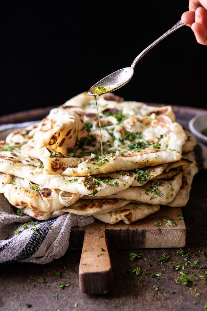 side angle photo of drizzling butter over Herbed Garlic Butter Naan 