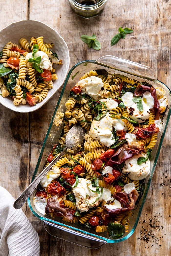 overhead photo of Caprese Pesto Pasta Bake with bowl of food on surface