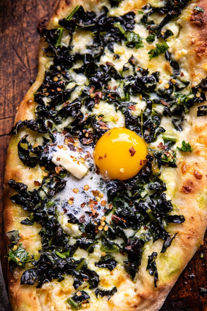 overhead close up photo of Khachapuri (Georgian Cheese Bread) with Kale and Herb Sauce