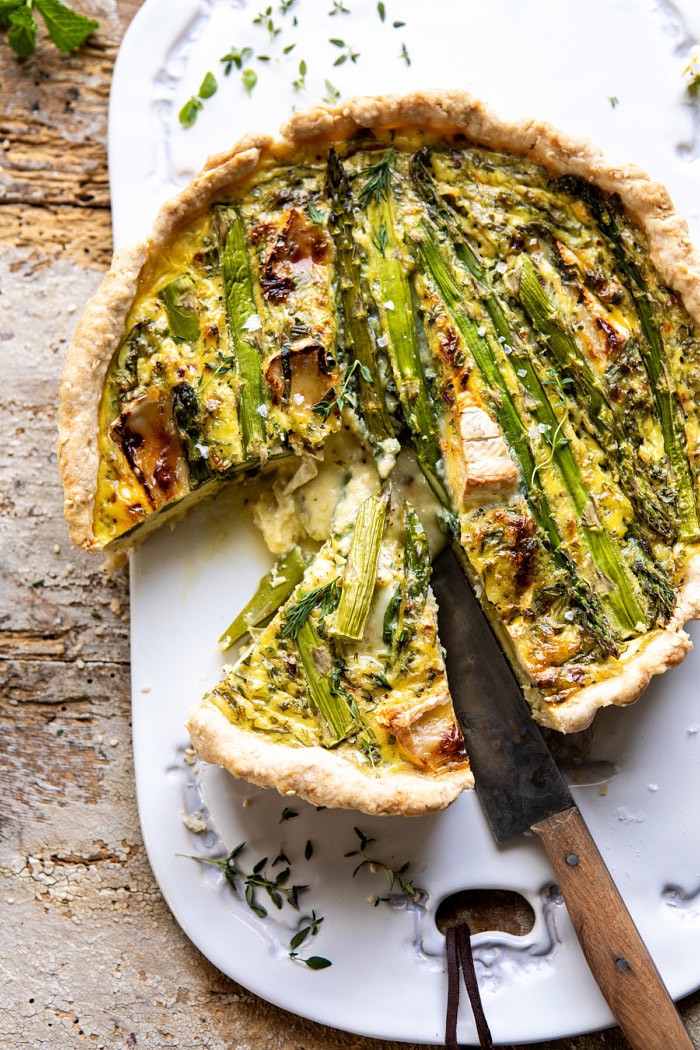 overhead photo of Asparagus and Brie Quiche with 1 slice cut and knife in quiche