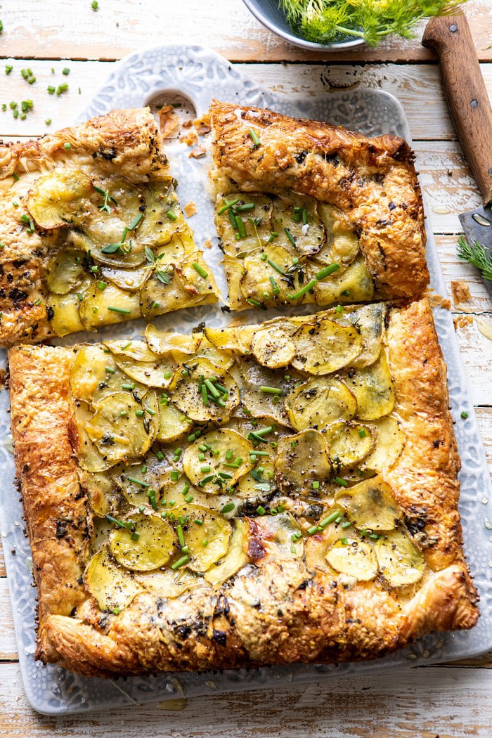 overhead photo of Cheesy Potato Chive Galette with 2 pieces cut and knife in photo