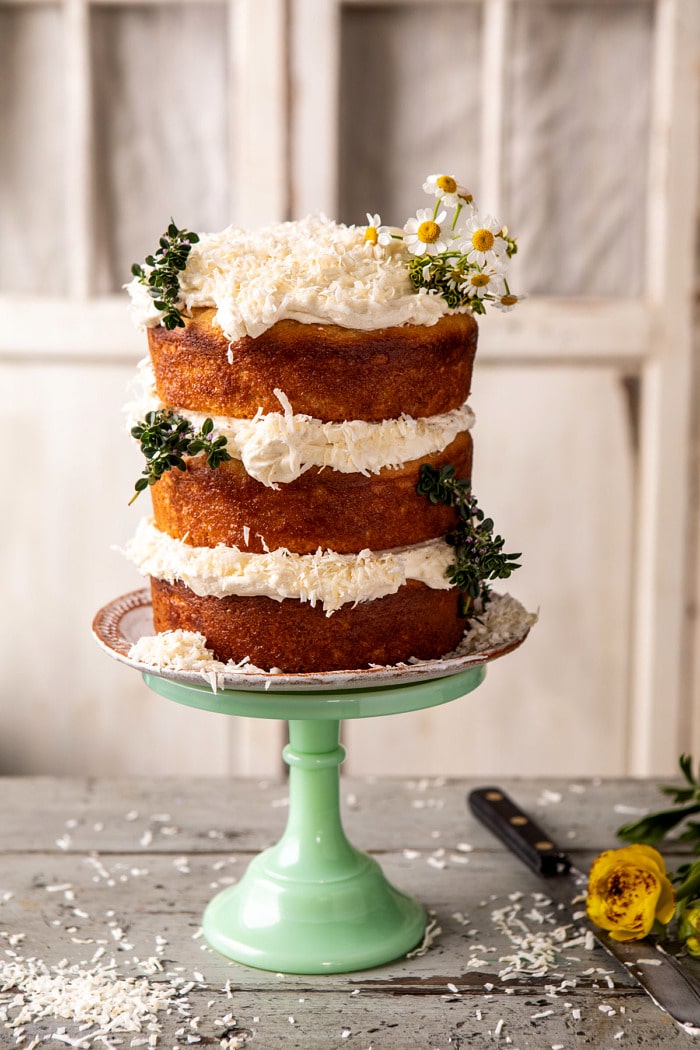 side angled photo of Lemon Coconut Naked Cake with Whipped Vanilla Buttercream on cake stand