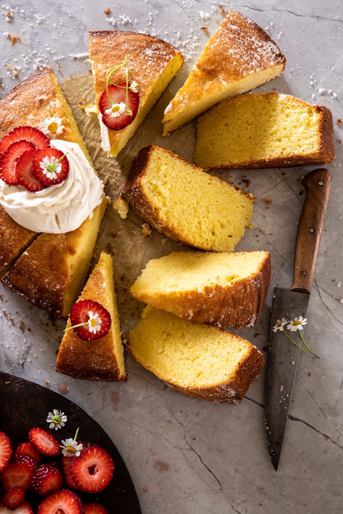 over head photo ofo Strawberry Chamomile Olive Oil Cake with Honeyed Ricotta and 8 slices cut from cake and knife in photo 