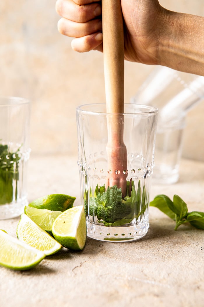 Muddling mint and basil in a glass