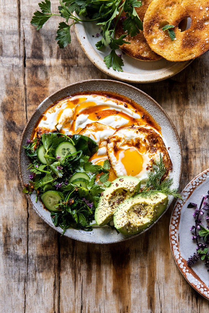 overhead photo if Turkish Eggs with Chile Butter and Whipped Feta with bagel and greens in photo