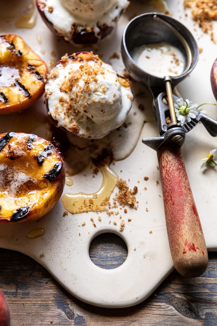 close up side angled photo of Browned Butter Grilled Peaches with Cinnamon Toast Brioche Crumbs on serving plate with ice cream scoop