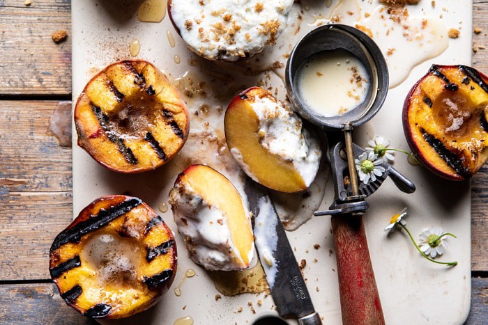 horizontal photo of Browned Butter Grilled Peach cut in half with Cinnamon Toast Brioche Crumbs 