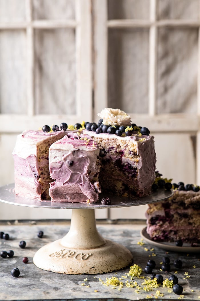 side angled photo of Bursting Blueberry Lemon Layer Cake with slices cut out