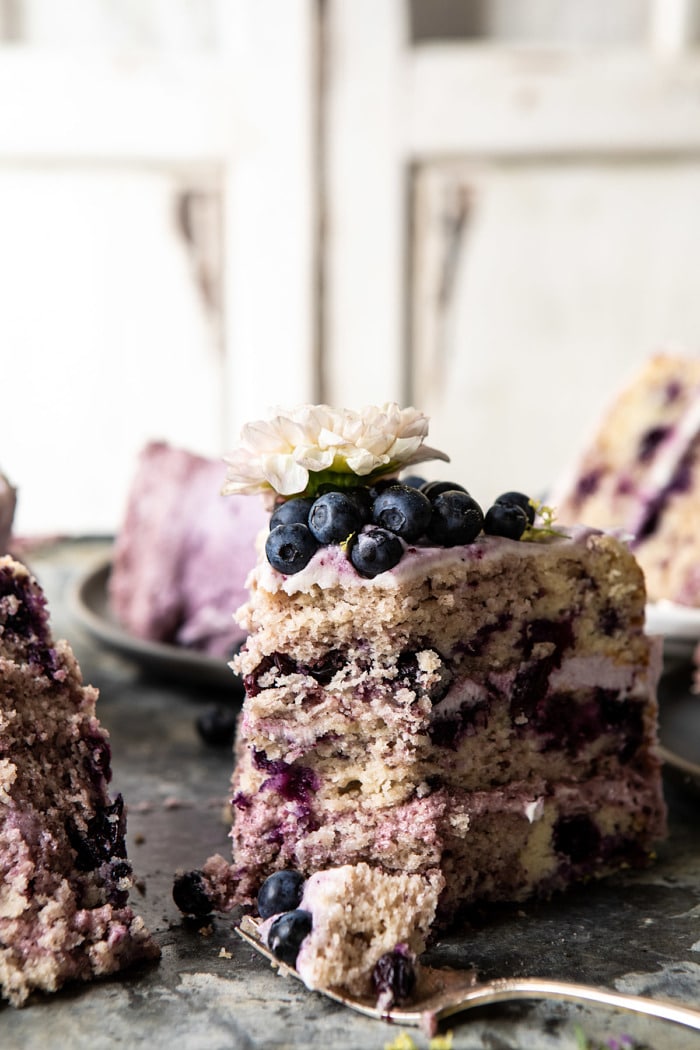side angled photo of Bursting Blueberry Lemon Layer Cake slices with bite taken out