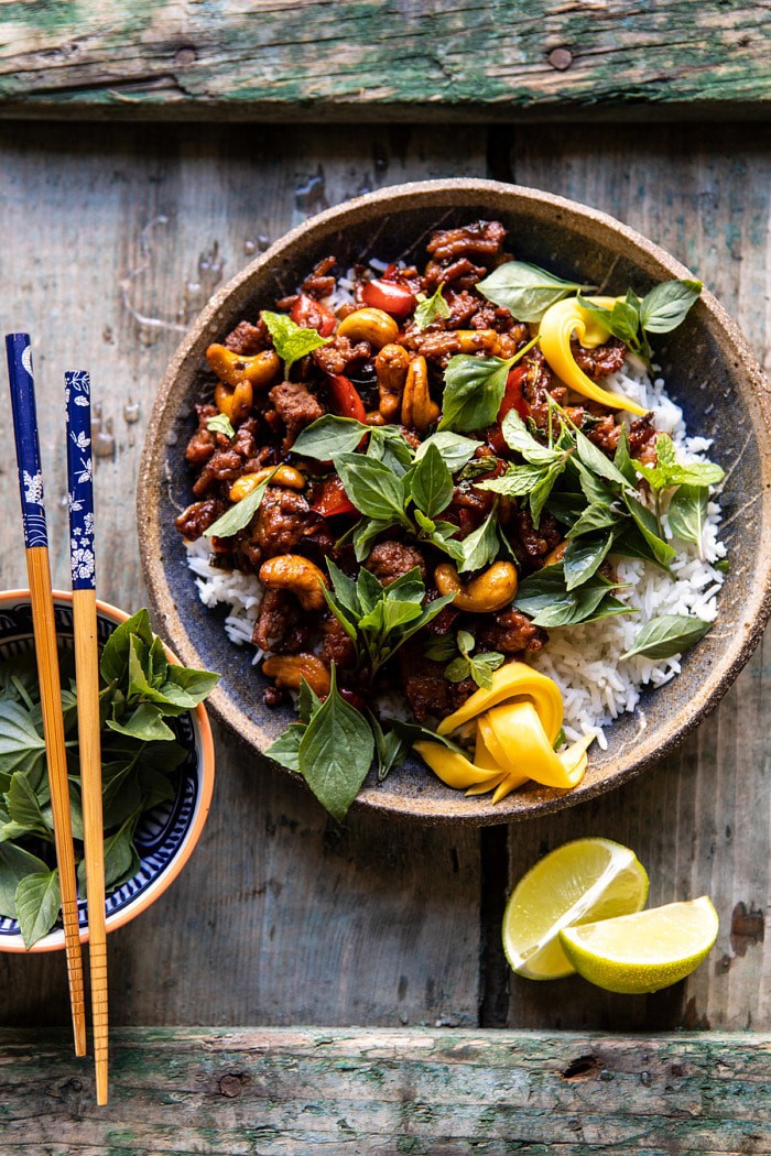 overhead photo of Better Than Takeout Sweet Thai Basil Chicken with chopsticks resting on bowl and limes on table