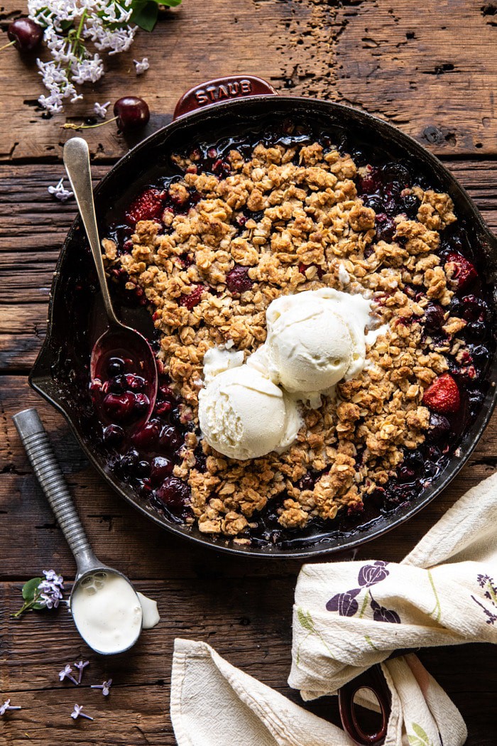 overhead photo of Buttery Cherry Berry Skillet Crisp with ice cream on crisp and spoon in skillet