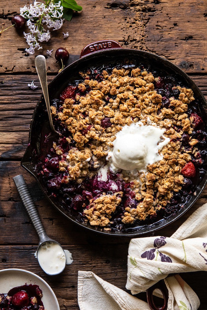 overhead photo of Buttery Cherry Berry Skillet Crisp in skillet with 1 scoop of ice cream and spoon in skillet