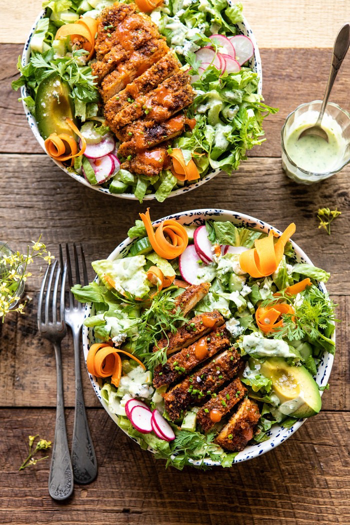 overhead photo of Crispy Buffalo Ranch Chicken Salad with Goddess Dressing with dressing in jar and flowers on table