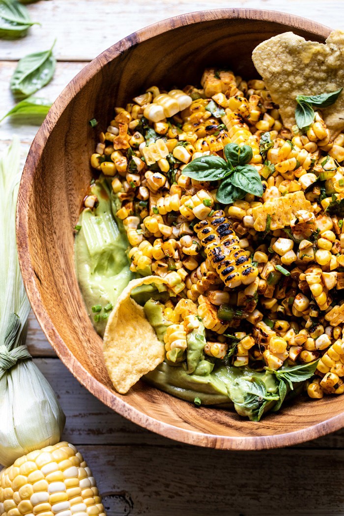 overhead close up photo of Grilled Street Corn Salad with Avocado Mayo with chip in bowl