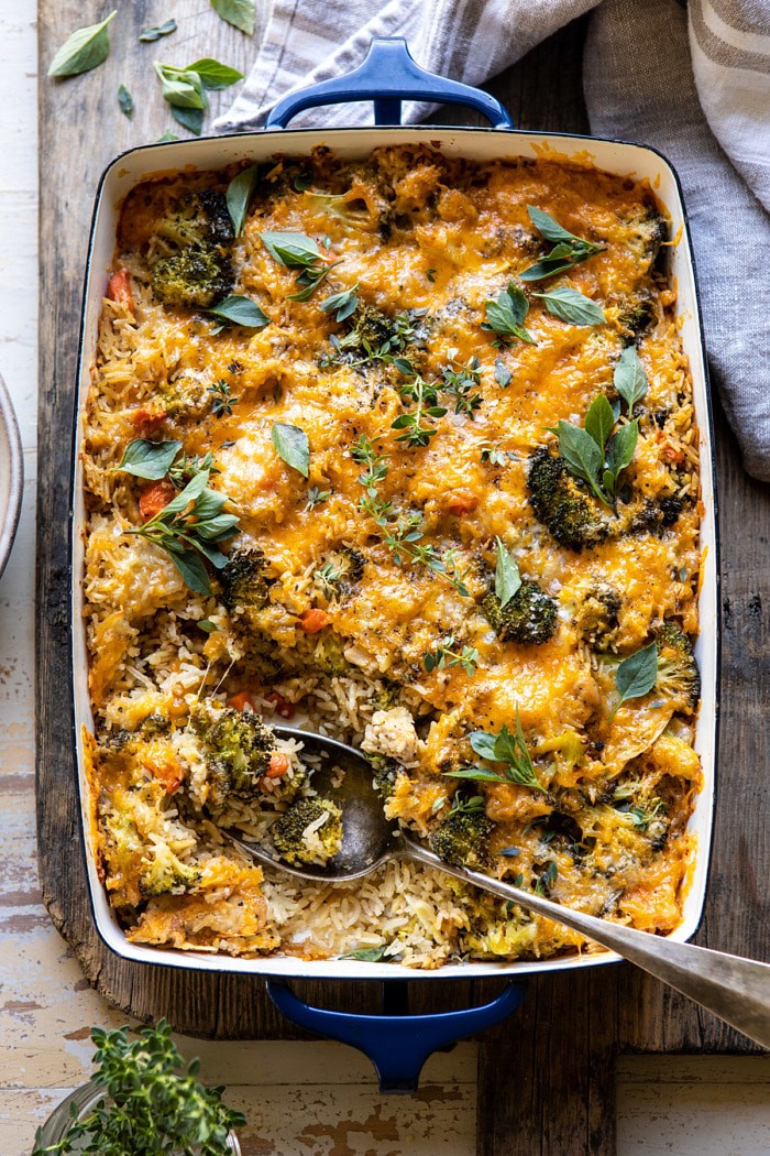 overhead photo of Broccoli Cheddar Chicken and Rice Casserole with serving spoon in casserole dish and portion of the rice removed from dish