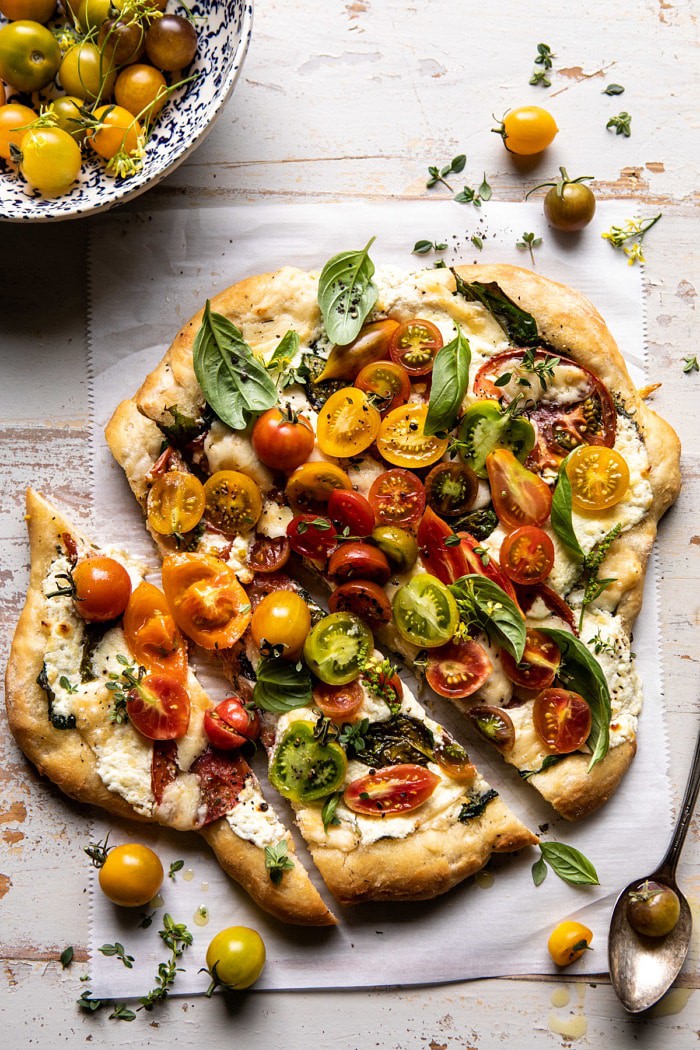overhead photo of Herbed Butter Heirloom Tomato Pizza with 2 pieces of pizza cut
