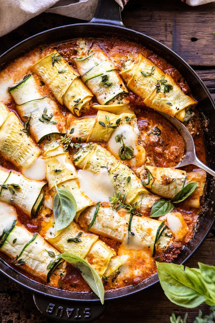overhead close up photo of Spicy Pesto and Cheese Stuffed Zucchini Involtini with spoon in baking dish