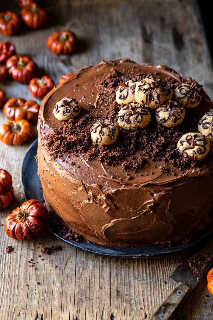 3/4 angle photo of Pumpkin Patch Chocolate Peanut Butter Cake with mini pumpkins on table