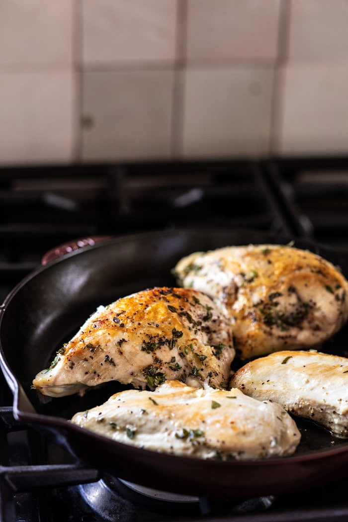 side angled photo of chicken cooking in skillet