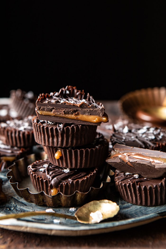 side angled photo of 6 Ingredient Milk Chocolate Salted Caramel Cups stack on top of each other with one caramel cup cut in half