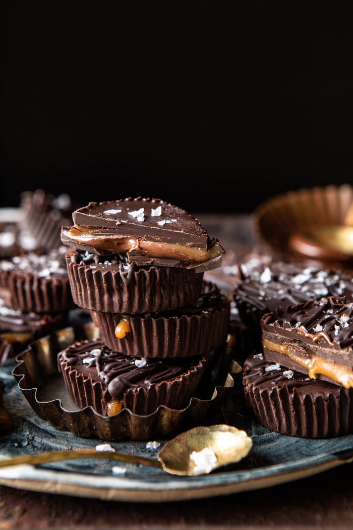 side angled photo of 6 Ingredient Milk Chocolate Salted Caramel Cups stack on top of each other with 1 chocolate cup cut in half