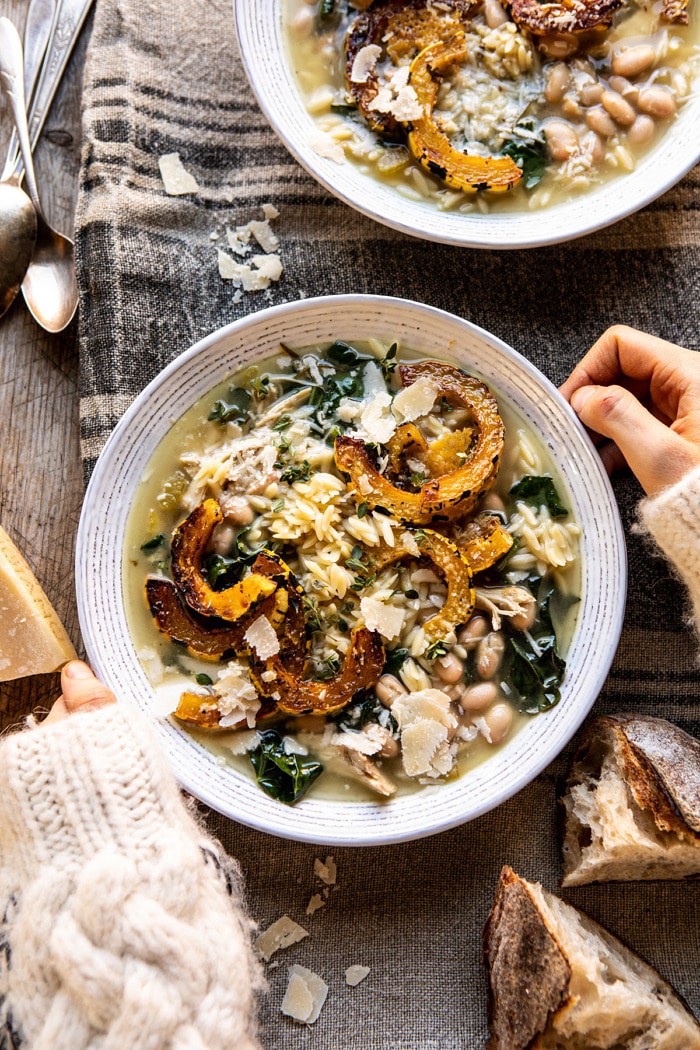 overhead photo Crockpot Parmesan White Bean Chicken Soup with Roasted Delicata Squash with hands on bowl 