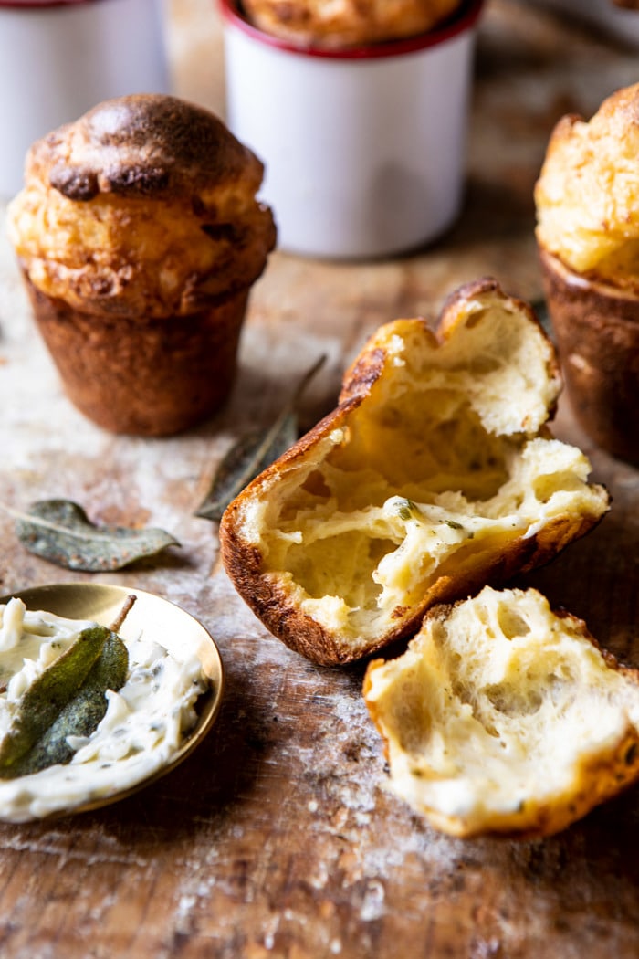 front on close up photo of Parmesan Popovers with Crispy Sage Garlic Butter broken in half to show the airy inside of the popover