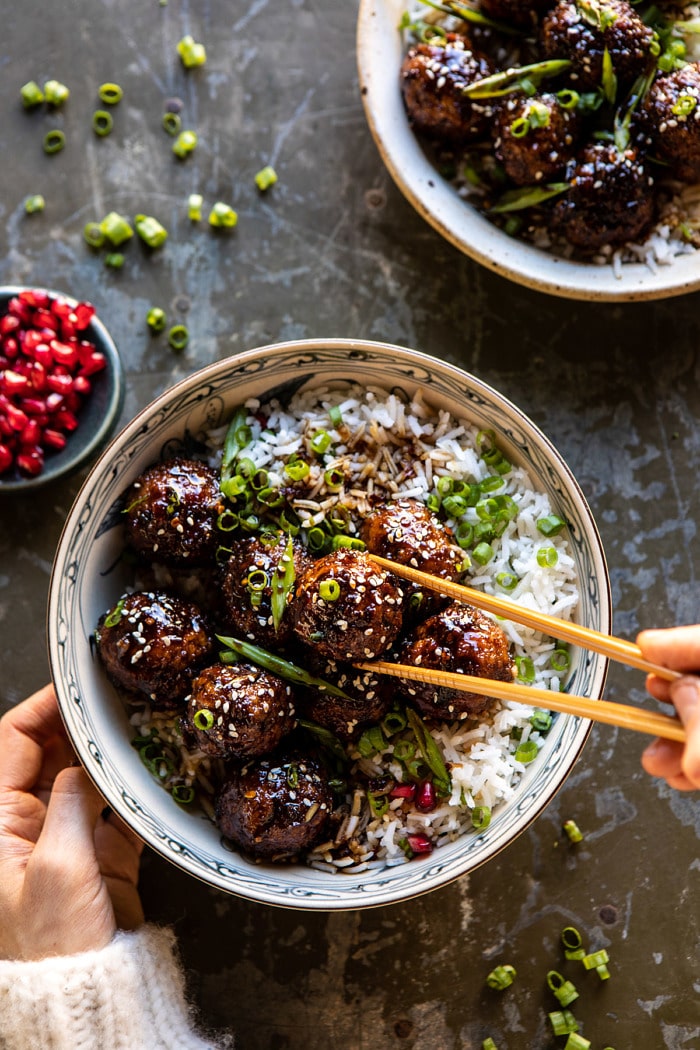 overhead photo of Weeknight Sticky Ginger Sesame Chicken Meatballs with hands on bowl and chopsticks picking up meatball