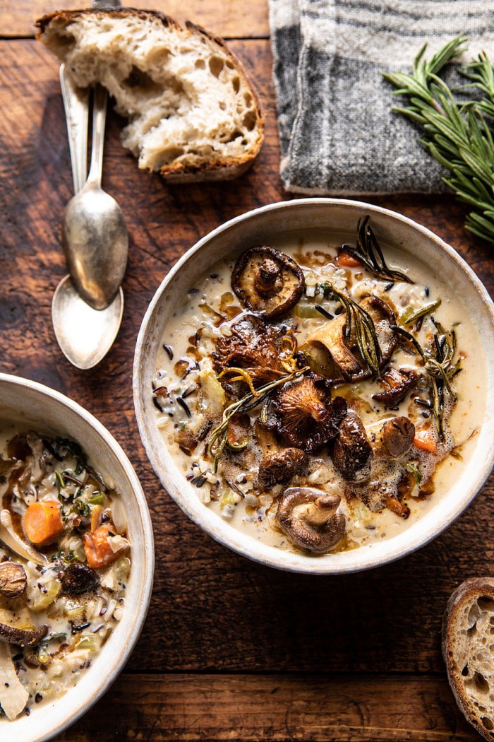 overhead photo of Creamy Wild Rice Chicken Soup with Roasted Mushrooms with bread and spoons on table next to soup bowls