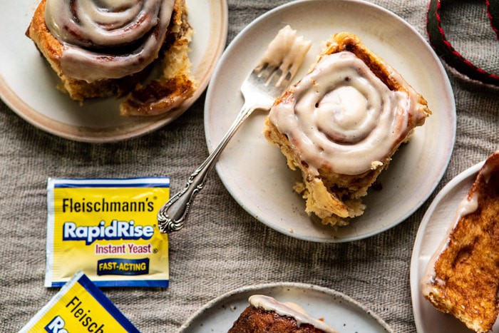 horizontal photo of Easy Gingerbread Brioche Cinnamon Rolls on plates with forks