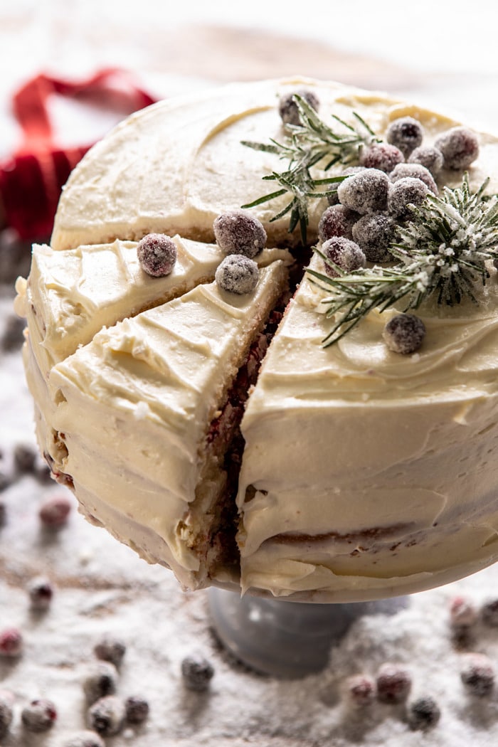 side angled close up photo of White Christmas Cranberry Layer Cake with 2 slices cut in cake